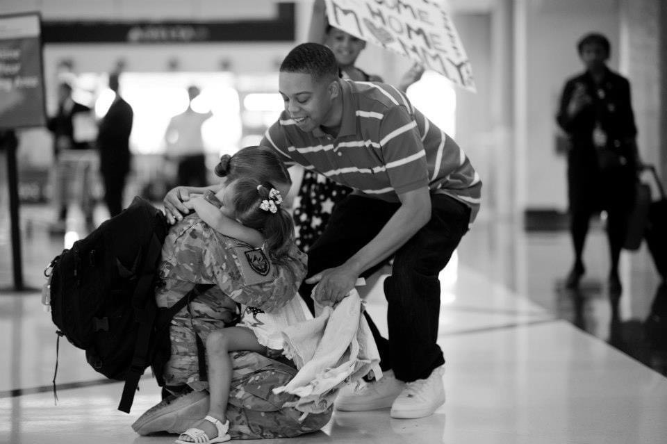 Master Sergeant Devan Taylor returns from her deployment and sits on her knees on the airport floor so she can be hugged by her children.